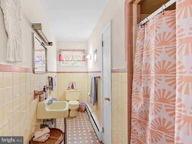 bathroom featuring sink, baseboard heating, a shower with curtain, toilet, and tile walls