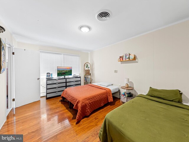 bedroom with light hardwood / wood-style flooring and crown molding