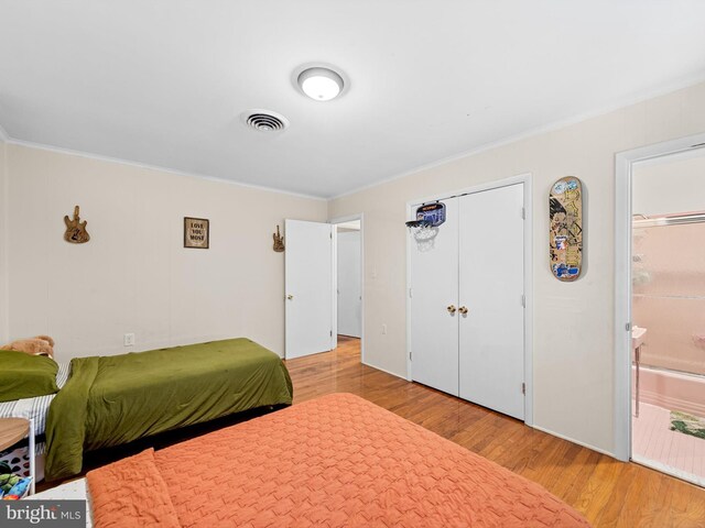 bedroom featuring ensuite bath, crown molding, and light hardwood / wood-style flooring