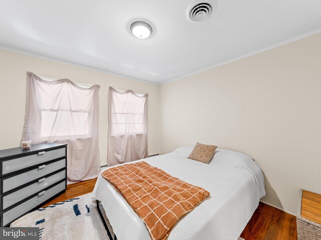 bedroom with wood-type flooring and ornamental molding