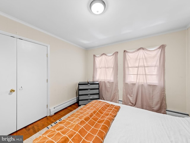 bedroom with light hardwood / wood-style floors, crown molding, a closet, and a baseboard heating unit