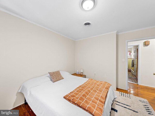 bedroom with wood-type flooring and ornamental molding