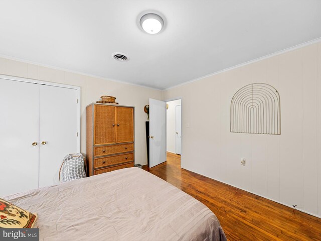 bedroom featuring ornamental molding, dark wood-type flooring, and a closet