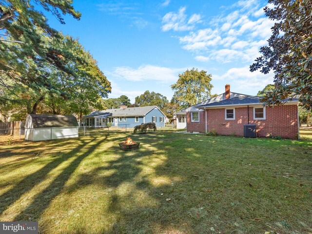 view of yard featuring a shed, a fire pit, and central AC unit