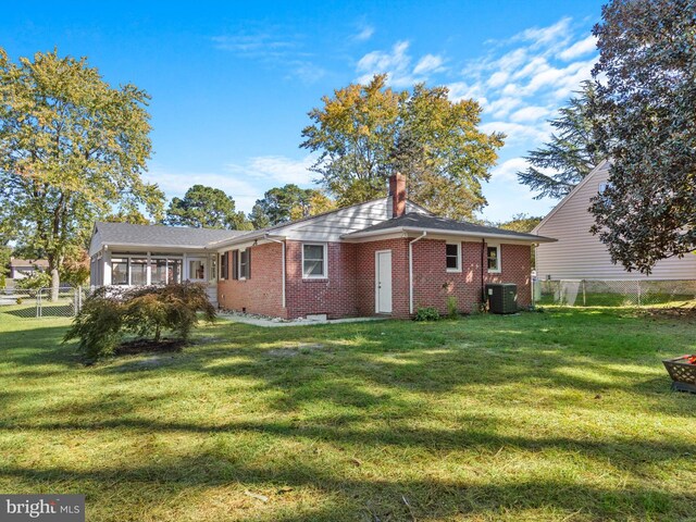 back of house with central AC and a lawn