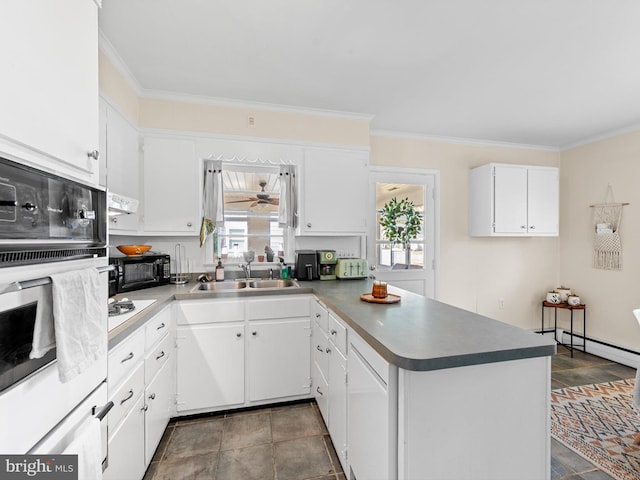 kitchen featuring white cabinetry, sink, kitchen peninsula, crown molding, and oven