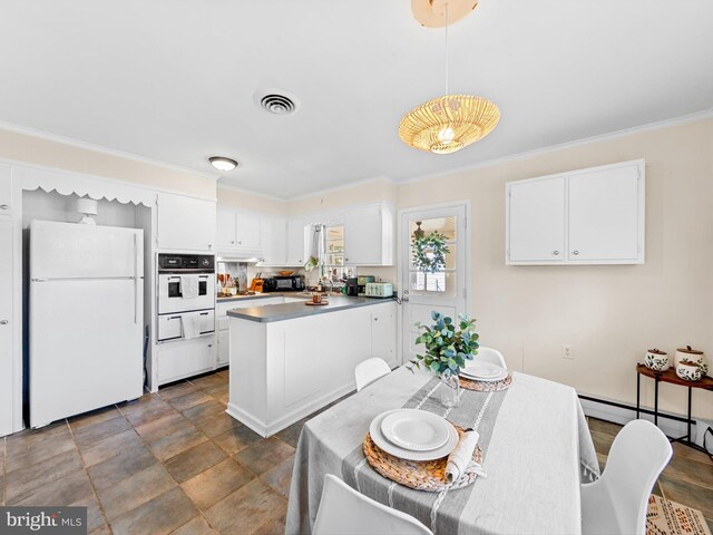 kitchen featuring white cabinets, white appliances, hanging light fixtures, and crown molding