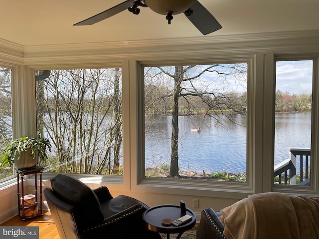 sunroom / solarium with ceiling fan and a water view