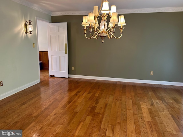 empty room featuring a chandelier, dark hardwood / wood-style floors, and ornamental molding