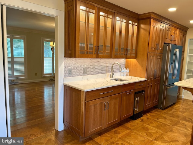 kitchen with decorative backsplash, stainless steel refrigerator with ice dispenser, light stone countertops, crown molding, and sink