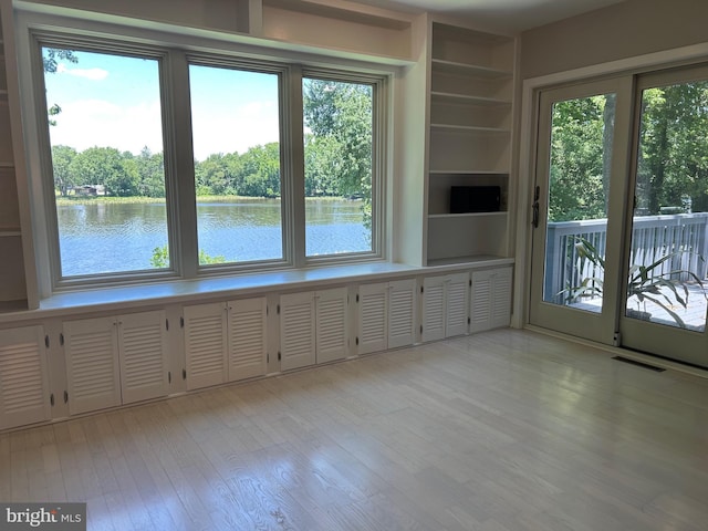 interior space with plenty of natural light, a water view, and light wood-type flooring