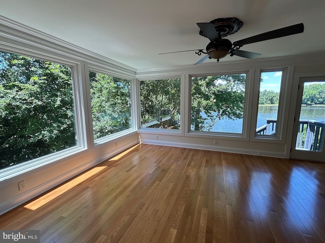 unfurnished sunroom with plenty of natural light, ceiling fan, and a water view