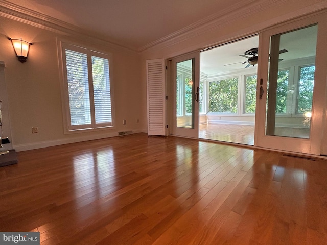 interior space featuring ceiling fan, wood-type flooring, crown molding, and a wealth of natural light