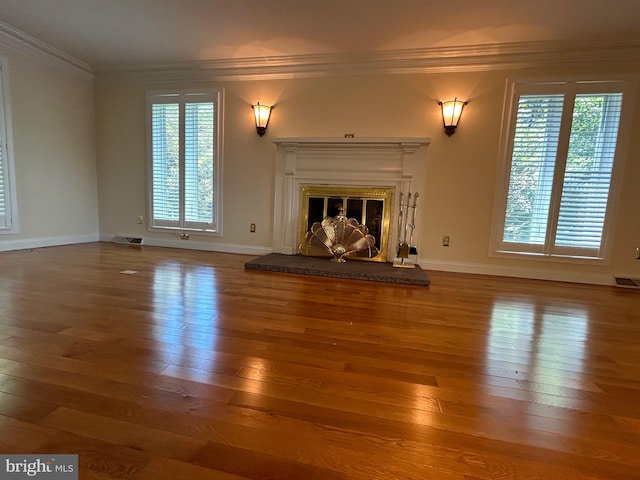 unfurnished living room featuring hardwood / wood-style floors, ornamental molding, and a healthy amount of sunlight