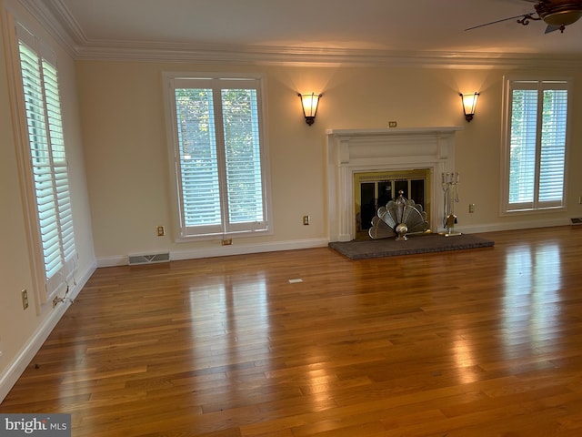 unfurnished living room featuring wood-type flooring, plenty of natural light, crown molding, and ceiling fan