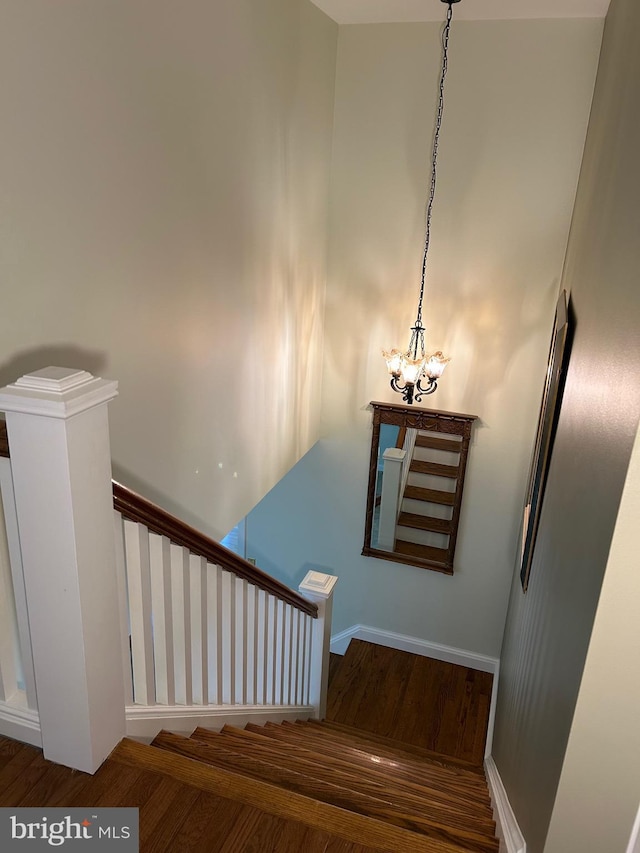 stairway with a notable chandelier and hardwood / wood-style flooring