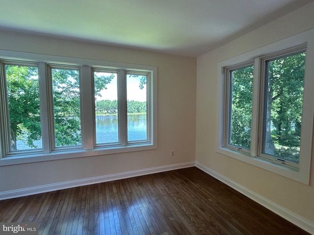 unfurnished room featuring dark hardwood / wood-style floors, a water view, and a wealth of natural light