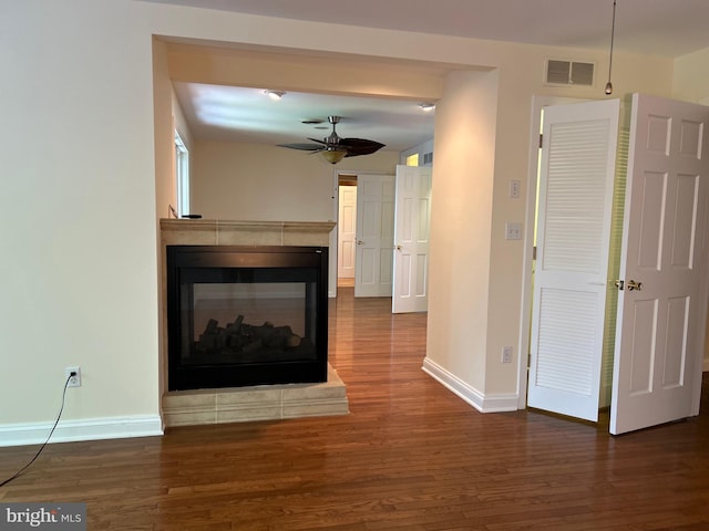 unfurnished living room featuring a multi sided fireplace, dark hardwood / wood-style floors, and ceiling fan