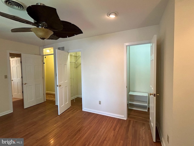 unfurnished bedroom with ceiling fan, dark hardwood / wood-style flooring, a spacious closet, and a closet