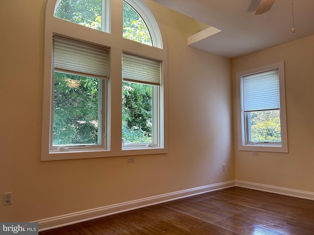 empty room featuring plenty of natural light, dark wood-type flooring, and ceiling fan