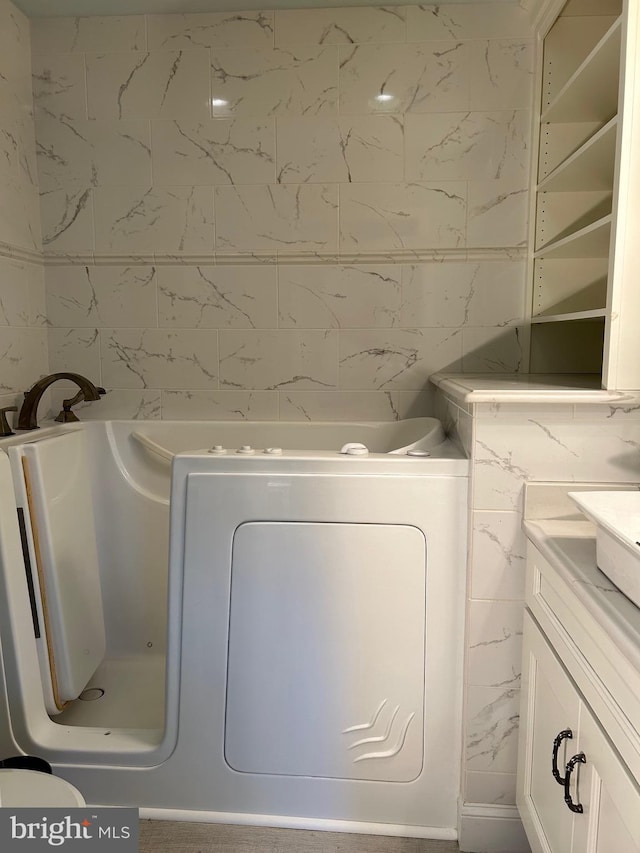 bathroom with vanity, washer / clothes dryer, tile walls, and a washtub