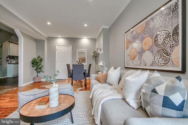 living room with a textured ceiling, light wood-type flooring, and crown molding