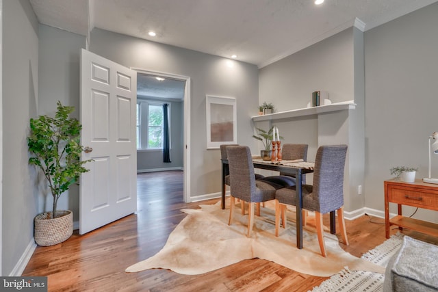 dining space with hardwood / wood-style floors and crown molding