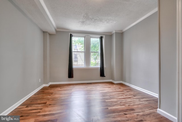 empty room featuring crown molding, a textured ceiling, and hardwood / wood-style flooring