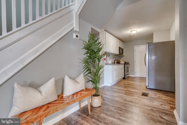 interior space with light hardwood / wood-style flooring, white cabinets, and stainless steel appliances