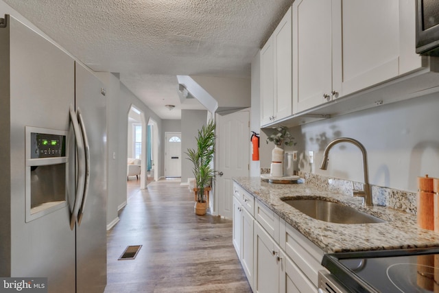 kitchen with stainless steel appliances, white cabinetry, light hardwood / wood-style floors, and sink