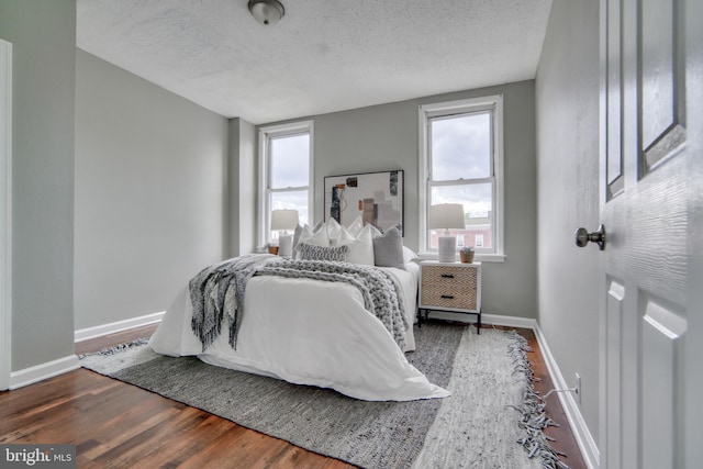 bedroom with multiple windows, wood-type flooring, and a textured ceiling