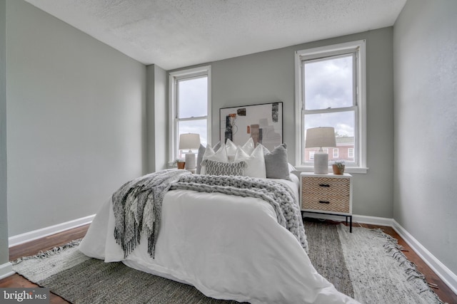 bedroom featuring hardwood / wood-style floors, a textured ceiling, and multiple windows