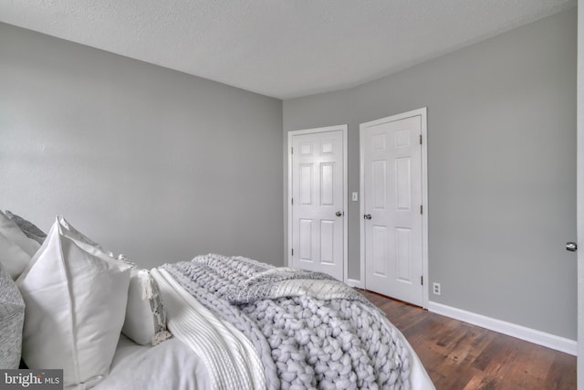 bedroom with a textured ceiling and dark hardwood / wood-style floors