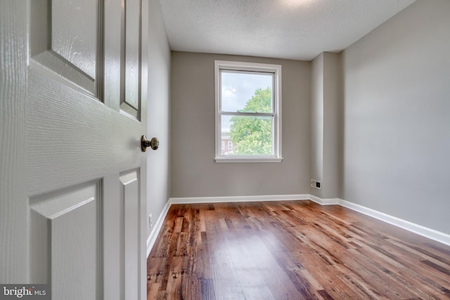 spare room featuring hardwood / wood-style floors and a textured ceiling