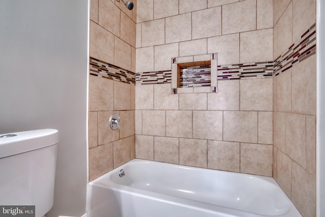 bathroom featuring tiled shower / bath and toilet