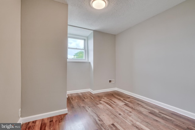 unfurnished room with a textured ceiling and light hardwood / wood-style floors