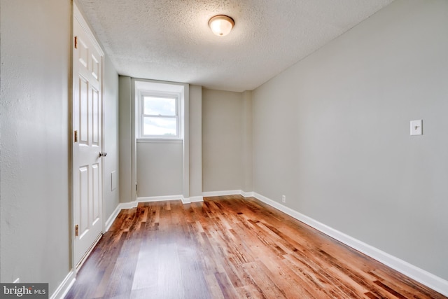 empty room with hardwood / wood-style floors and a textured ceiling