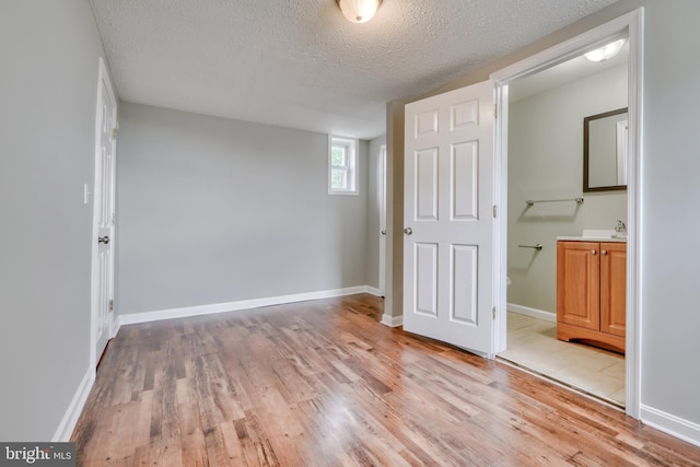 unfurnished bedroom featuring a textured ceiling, light hardwood / wood-style floors, and ensuite bathroom