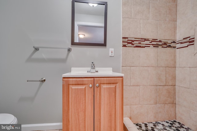 bathroom featuring tiled shower, vanity, and toilet