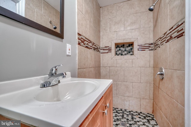 bathroom with tiled shower and vanity