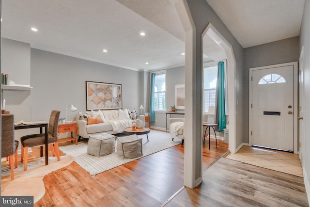 foyer with a textured ceiling, light hardwood / wood-style flooring, and ornamental molding