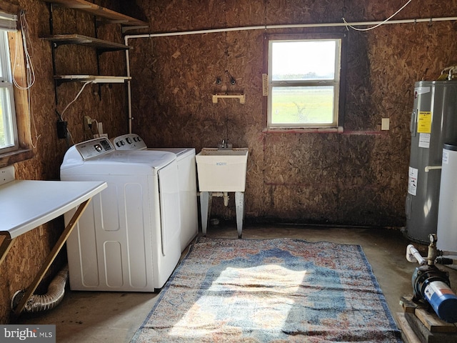 clothes washing area with electric water heater, sink, and washer and dryer