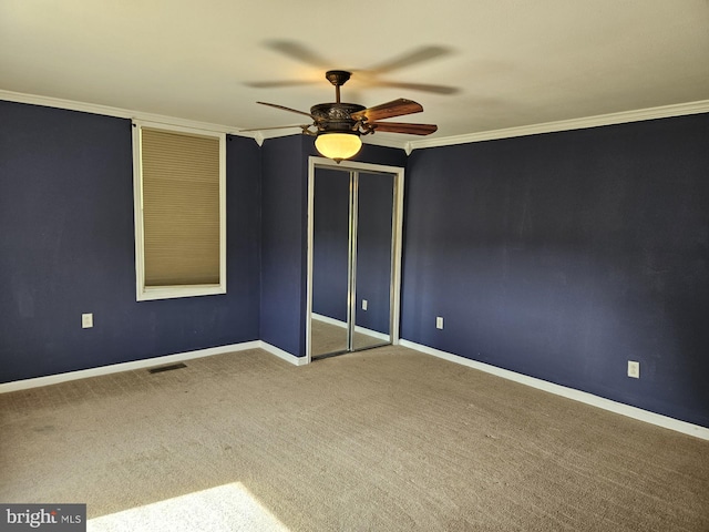 unfurnished bedroom featuring ceiling fan, ornamental molding, a closet, and carpet floors