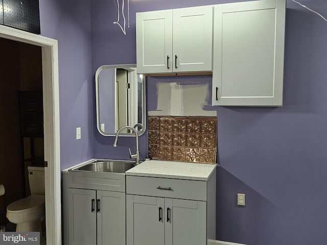 bathroom with toilet, vanity, and tasteful backsplash