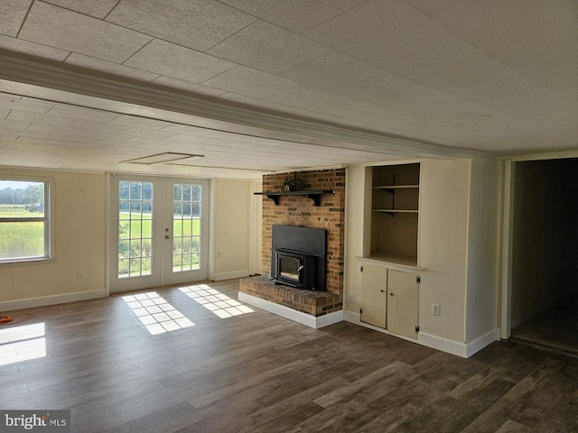 unfurnished living room featuring wood-type flooring, a wood stove, and french doors