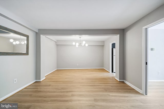 empty room with light hardwood / wood-style flooring and an inviting chandelier