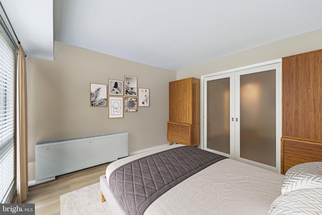 bedroom with radiator heating unit and light hardwood / wood-style flooring