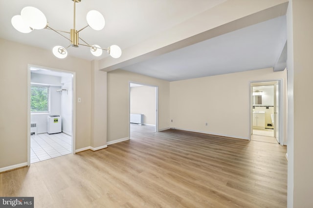 unfurnished living room featuring radiator, a notable chandelier, and light hardwood / wood-style flooring