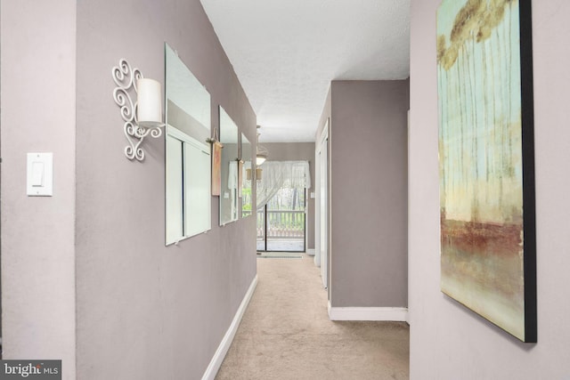 corridor featuring a textured ceiling and light colored carpet