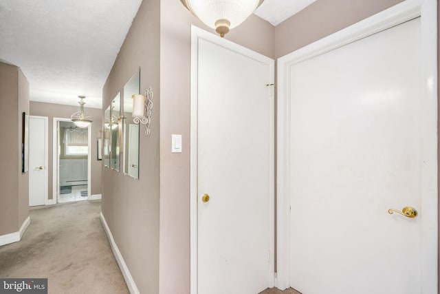 hall with light carpet and a textured ceiling